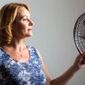Frau mit Hitzewallungen vor einem Ventilator